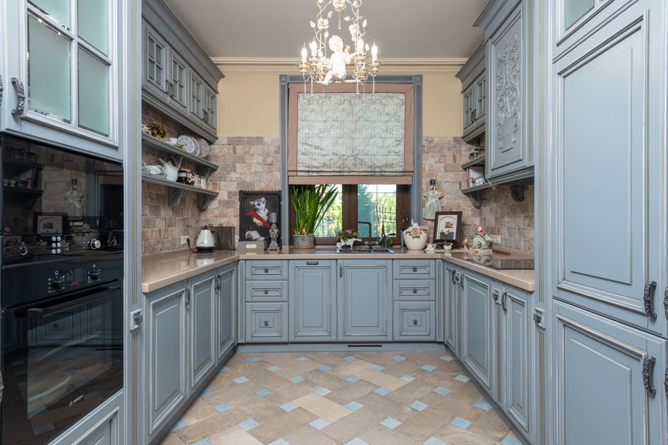 Discover an elegant vintage-style kitchen with classic cabinets and ornate chandelier.